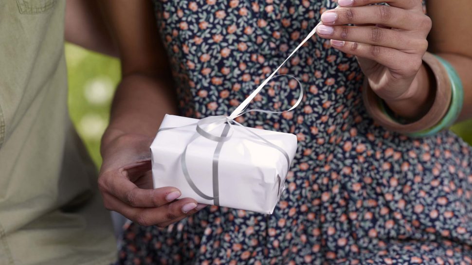 A girl unties a ribbon on a Christmas present. 