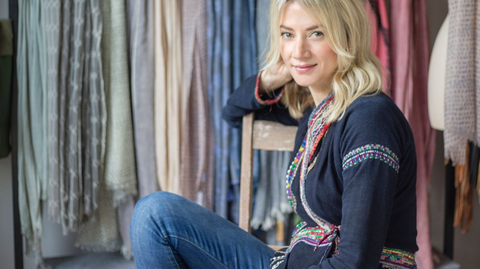 Jackie sitting on a chair in front of a beautiful array of clothing on a rack